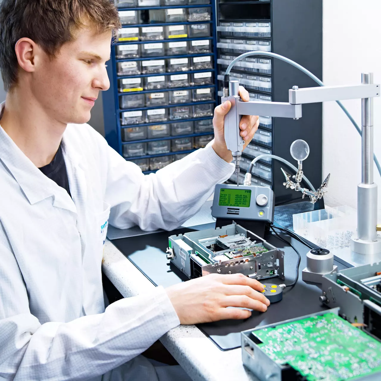 Technician using a pneumatic precision screwdriver to assemble a printed circuit board